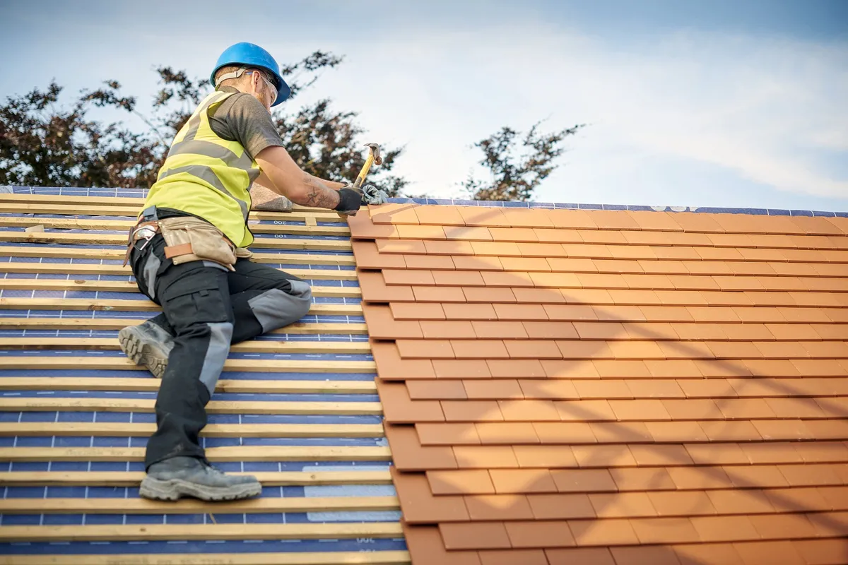 Ridge capping being re-bedded and repointed on a tiled roof